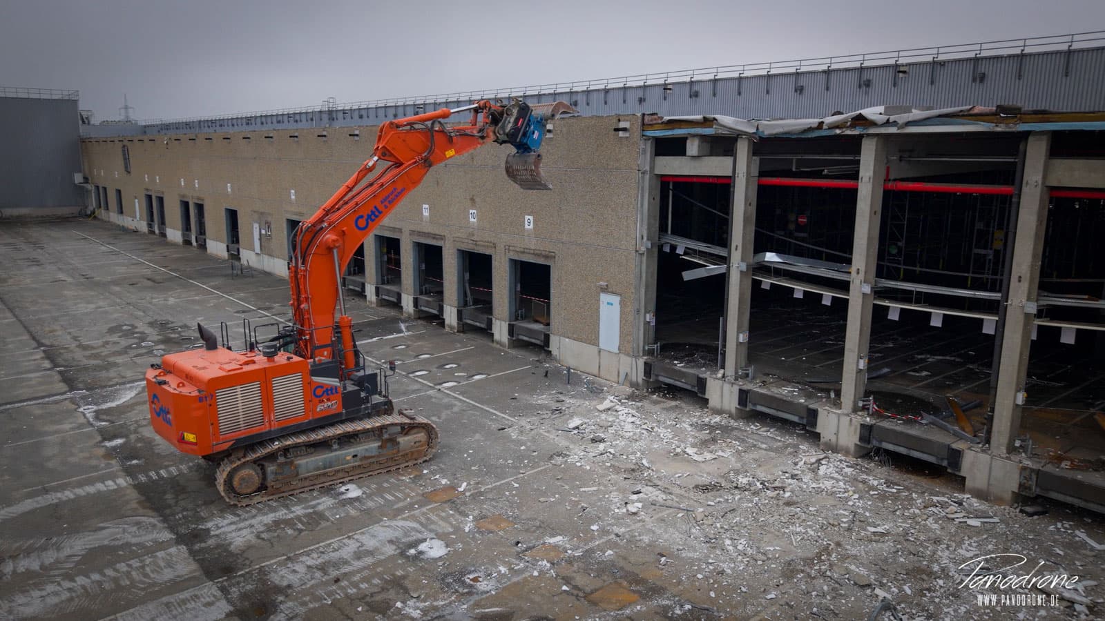 Drohnenaufnahme einer Baustelle – Abrissbagger beim Rückbau einer Gewerbehalle